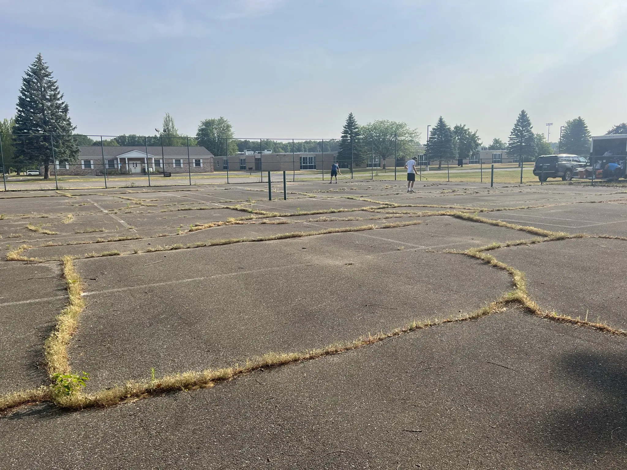 Cracked asphalt parking lot with weeds