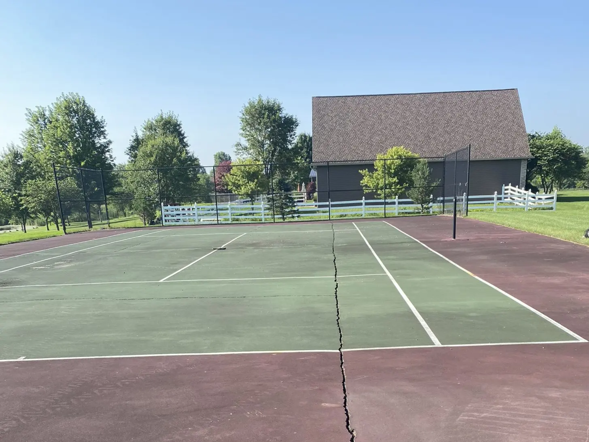 Cracked outdoor tennis court by rural barn